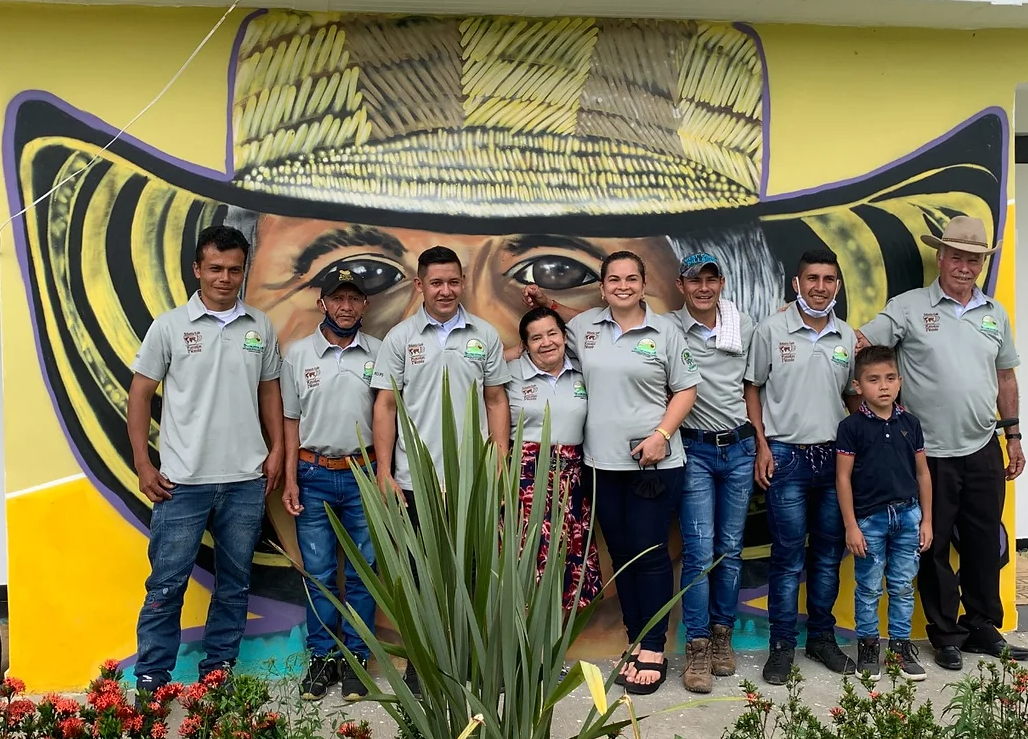 Asociación de Productores Ecológicos de Planadas (ASOPEP) cooperative members pose in front of a mural at the group’s headquarters in Planadas, Colombia. Credit: Root Capital.