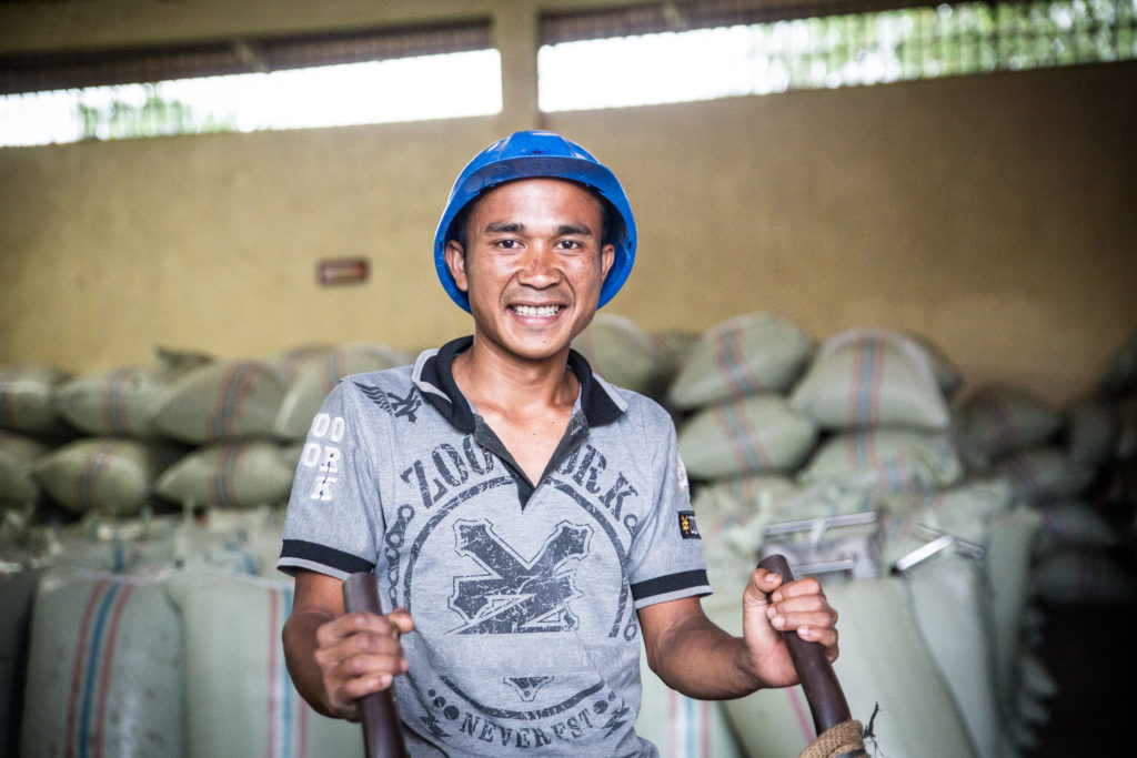 Juliman, a worker at the Kopepi Ketiara Cooperative, the bagged whole dried coffee in the warehouse.
 (Photo: Blake Dunlop)