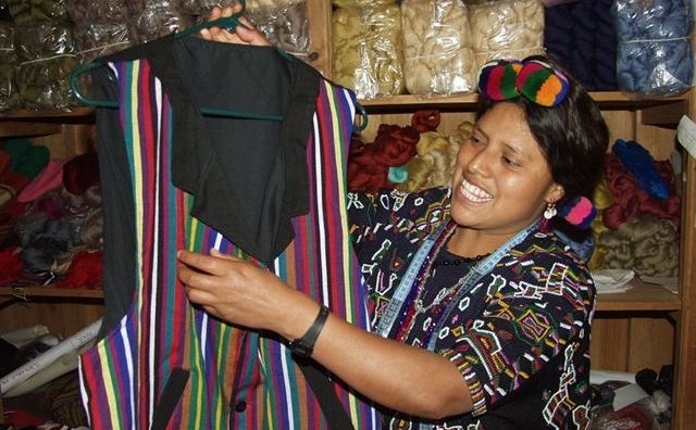 An artisan member of Asociación Chajulense proudly displays a coat she's made.