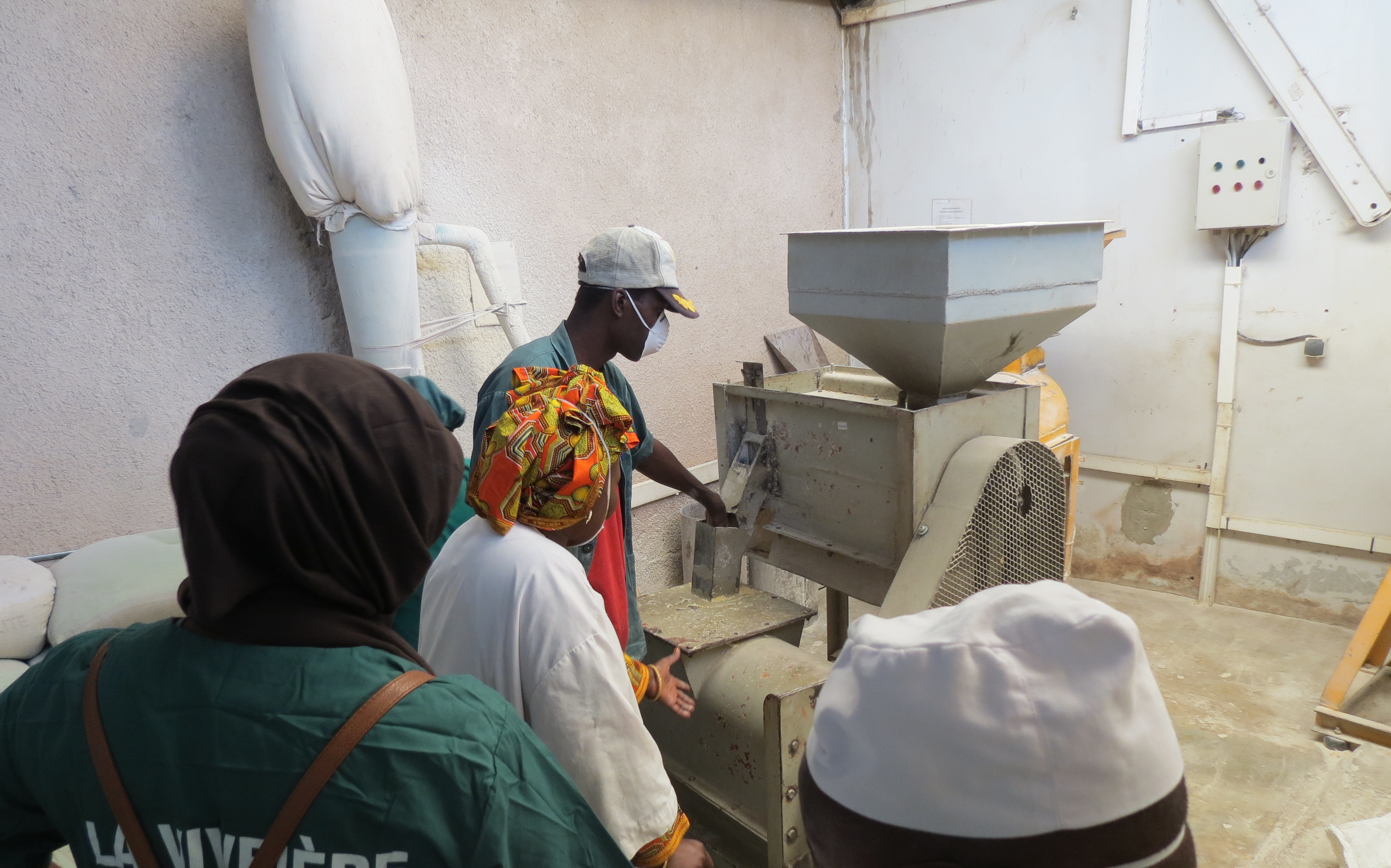 Bineta and employees of La Vivriére demonstrate how to use the machinery used to process millet flour.
