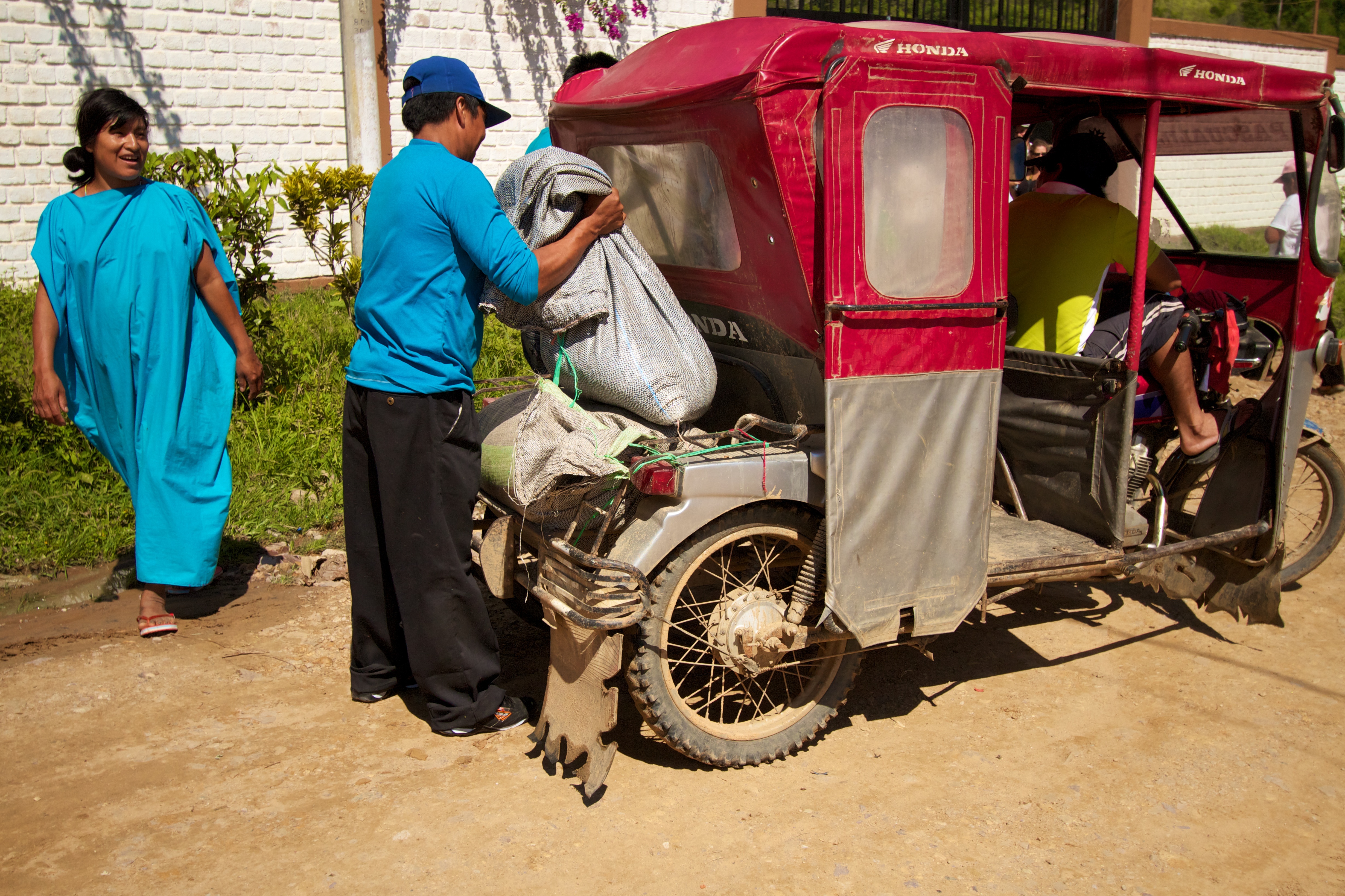 Employees of Pangoa unload coffee from a mototaxi