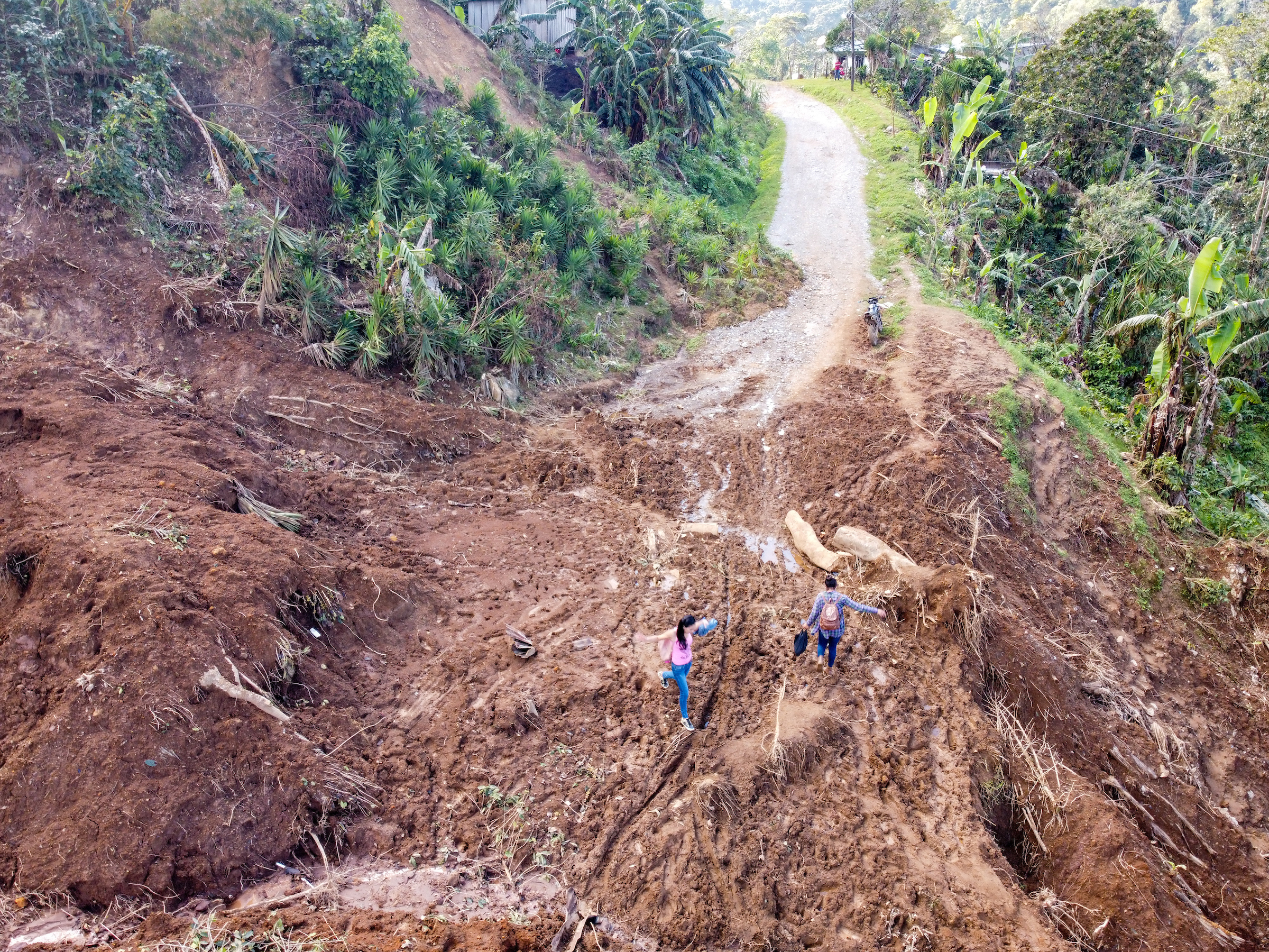Women clamber over a road washed out by a landslide in San Luis Planes after Hurricane Iota.
