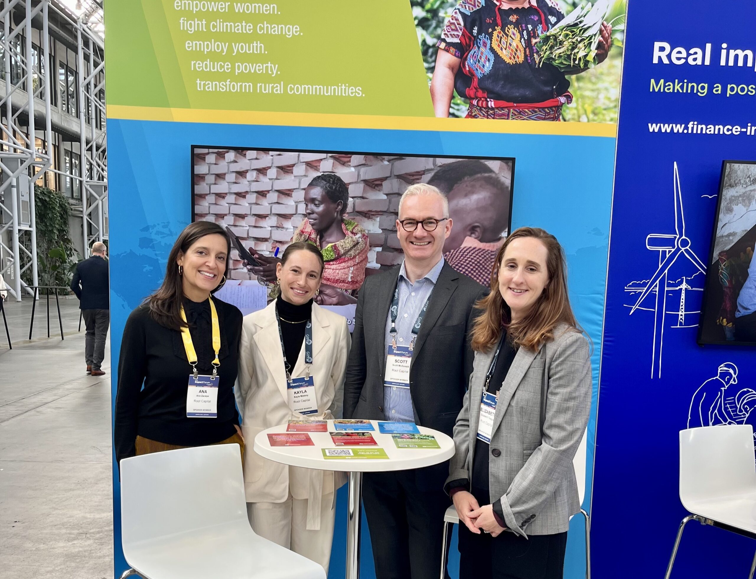  Ana Zacapa (Root Capital Chair Board), Kayla Massey (Senior Associate of Supporter Engagement), Scott McDonald (Chief External Affairs Officer), and Lizzie Teague (Director of Climate Resilience), pose at the Root Capital booth at the GIIN Forum hosted in Copenhagen in 2023. Credit: Root Capital.